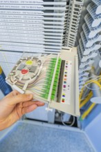 Hand holding a fiber optic cabling module in a technical environment, optical fiber