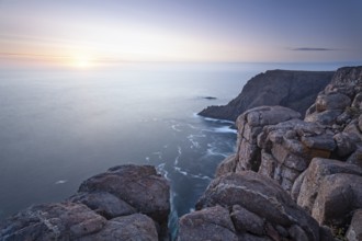 Long exposure shows sunset over the cliffs of Cape Raoul. Golden light hits the sea and colors the