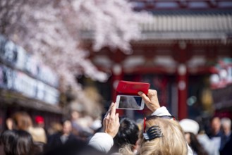 Tourist taking pictures with her cell phone, numerous visitors on Nakamise-dori shopping street,