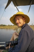 Tourist, photographer, young man with camera on a boat trip, in the evening light, Thamalakane