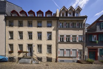 Historic buildings, houses, downpipes, façade with windows, dormers, stairs and doors, paving stone