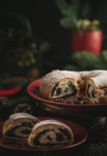 Sliced poppy seed cake on red plate surrounded by Christmas decoration