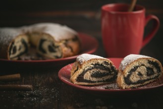 Poppy seed cake with red crockery and cinnamon sticks on wooden background