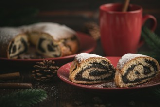 Poppy seed cake on a red plate surrounded by pine branches and a cup