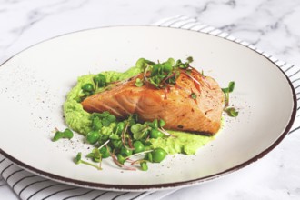 Delicious grilled salmon is placed elegantly on creamy green pea puree. Fresh microgreens and peas
