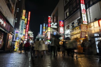 Busy pedestrian zone with many shopping centers and stores, illuminated with lots of neon signs at