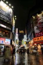 Busy pedestrian zone with many shopping centers and stores, illuminated with lots of neon signs at