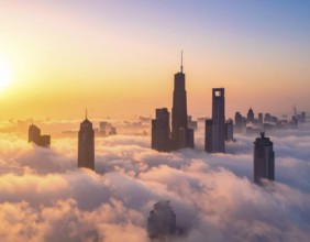City scape emerging from a dense enveloping fog in sunrise and skyscrapers piercing the haze, big
