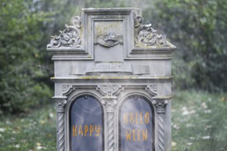 Tombstone at a cemetery with (added) text HAPPY HALLOWEEN (digitally reworked)