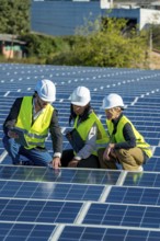 Diverse team of engineers and technicians inspecting and discussing solar panel installation and