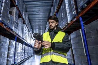 Worker wearing a safety vest and jacket operating a barcode scanner, managing inventory and