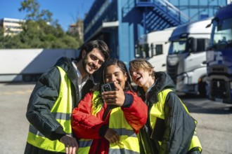 Group of smiling logistics workers wearing protective vests and warm jackets creating a cheerful