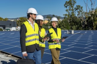 Team of diverse engineers and technicians wearing hard hats and high visibility vests inspecting a