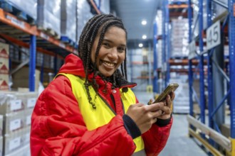 Smiling female worker managing cold storage inventory, checking orders and ensuring efficient