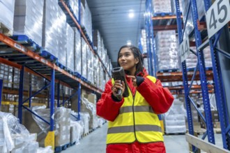 Woman wearing protective cold weather gear and a high visibility vest operating a barcode scanner,