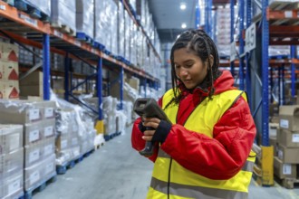Logistics worker wearing warm clothing and a safety vest performing inventory checking with a