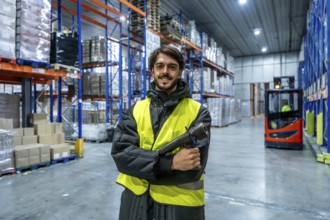 Man smiling inside a frozen warehouse, wearing a warm jacket and high visibility vest, holding a