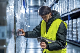 Worker wearing a safety vest and warm jacket, scanning a barcode on wrapped merchandise in a cold