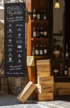 Italian wine shop with wine bottles and wooden boxes in rustic surroundings, Tuscany, Italy