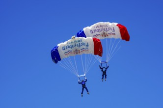 Skydivers during an aerial acrobatic performance as part of an air show at the Fliegerbergfest of