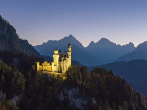 Neuschwanstein Castle at dusk with mountain views and surrounded by forest