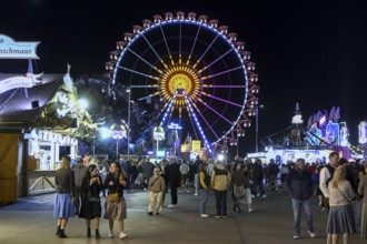 Oktoberfest visitors at night with the Ferris wheel in the background, Munich, Bavaria, Germany
