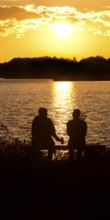Two men sitting on a bench at sunset at Lake Gudelack, Lindow (Mark), Stechlin-Ruppiner Land nature
