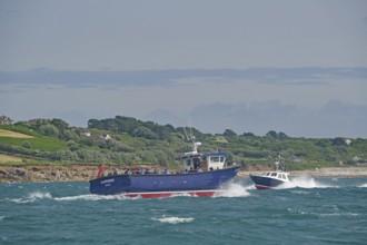 Two boats carrying passengers fight the waves near a green coastal landscape, Isles of Scilly,
