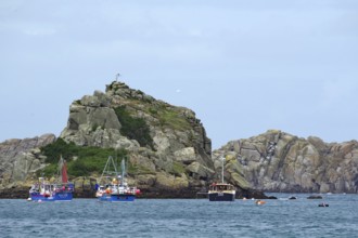 Small boats on the sea surrounded by rough rocky coast, Isles of Scilly, Cornwall, Great Britain
