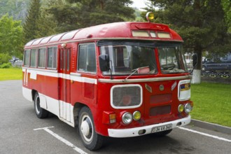 Red retro bus in a parking lot surrounded by trees and green nature, PAZ-672, minibus from Soviet