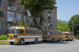 Three orange buses parked in a row on a sunny street next to a building, PAZ-672, minibus from