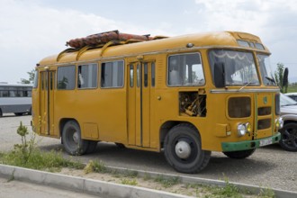 Vintage yellow bus on a road surrounded by a meadow, under cloudy sky, PAZ-672, minibus from Soviet