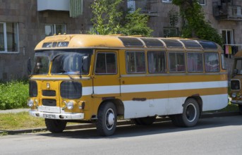 An old retro bus in orange parked on a street next to a building, PAZ-672, minibus from the Soviet