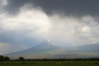 Mountain landscape with snow-capped peak under dramatic sky and dark clouds, Little Ararat, located