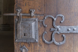 Detail of an old wooden door with metal fittings and lock in a rustic, historic atmosphere,