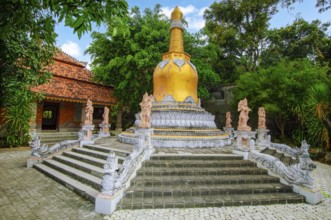 Large golden golden stupa on pedestal with steps, in front of guardian figures Buddhist monastery