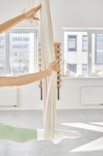 Individual practice stretching exercises using a hammock in a well-lit fitness studio. The scene