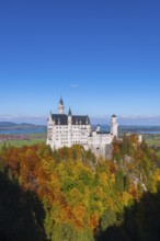 Neuschwanstein Castle overlooks the autumn trees and blends harmoniously into the landscape,