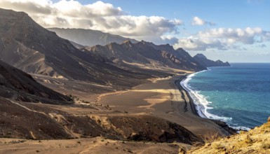 Desert landscape converges with ocean along a rugged coastal area, shore break at cliffs, blue
