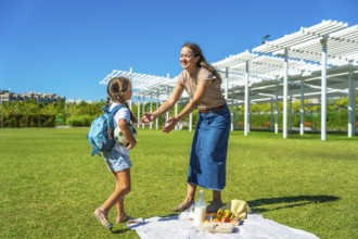 Mother and daughter enjoying a happy summer picnic in a park, parents spending quality time with