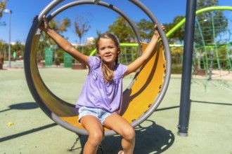 Happy child swinging on a round playground swing, enjoying outdoor activity on a sunny day,