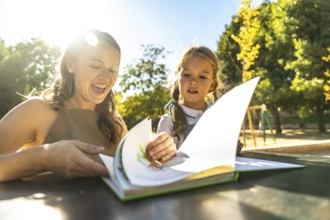 Mother and daughter engaging in a fun reading activity, turning pages of a colorful book while