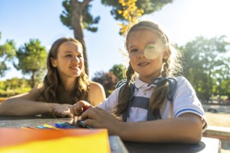 Young daughter and her mother enjoying a sunny day outdoors at the school playground, the child