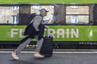 Flixtrain train on track 2 in Essen main station, passenger runs with luggage to reach his train,