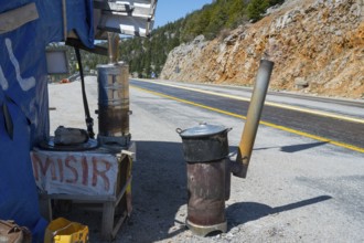 Temporary stand with ovens on the side of the road in mountainous surroundings, on the left