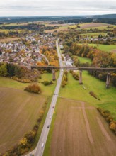 River and road criss-cross autumnal landscape with bridge and nearby village, Dornstetten,
