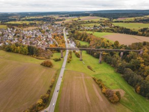 Country road crosses under a bridge in an autumn landscape with fields and villages, Dornstetten,