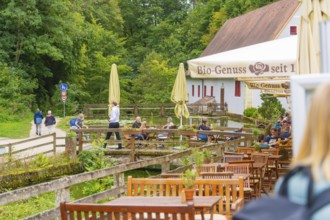 People relax in a café with a view of walkers in the countryside, Wimsener Höhle, Hayingen, Germany