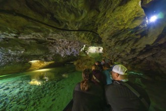 Group on a boat expedition exploring the fascinating waterways in a cave, Wimsener Höhle, Hayingen,