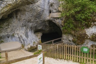 Wooden fence in front of the dark entrance of a cave in a rocky environment, Wimsener Höhle,